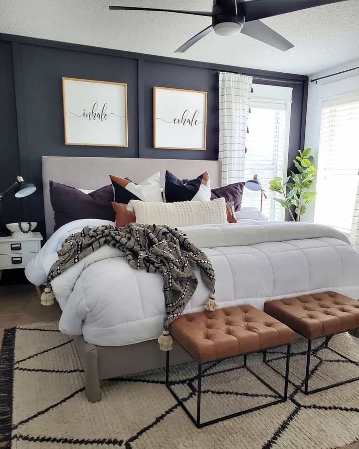 a bedroom with black walls, white bedding and brown foot stools in front of the bed