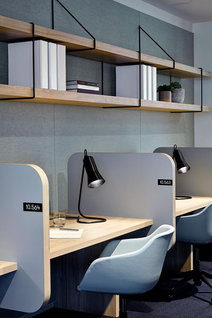 an office cubicle with three desks and two chairs next to each other in front of bookshelves