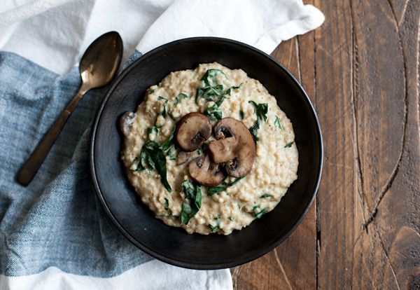 oatmeal with mushrooms and spinach in a black bowl on a wooden table