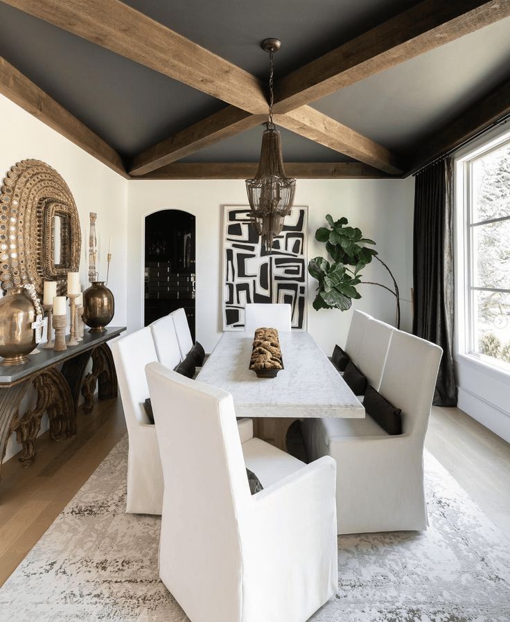 a dining room table with white chairs and a chandelier hanging from the ceiling