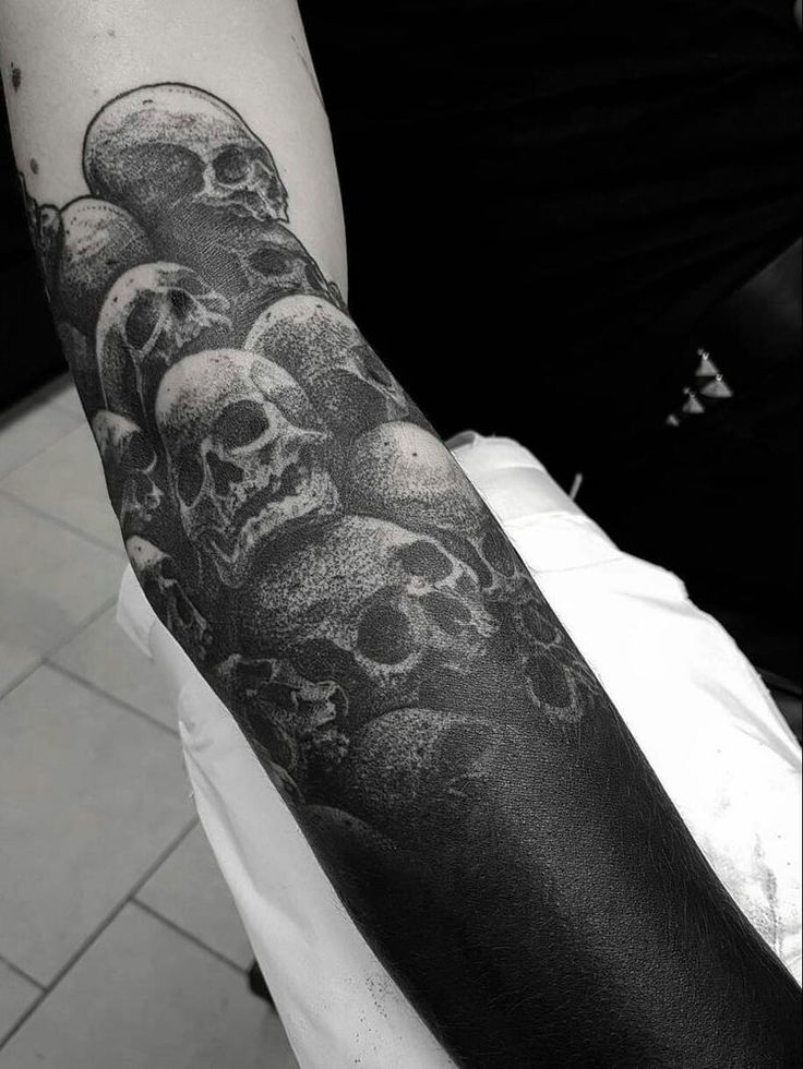 a man with a black and white tattoo on his arm that has skulls all over it