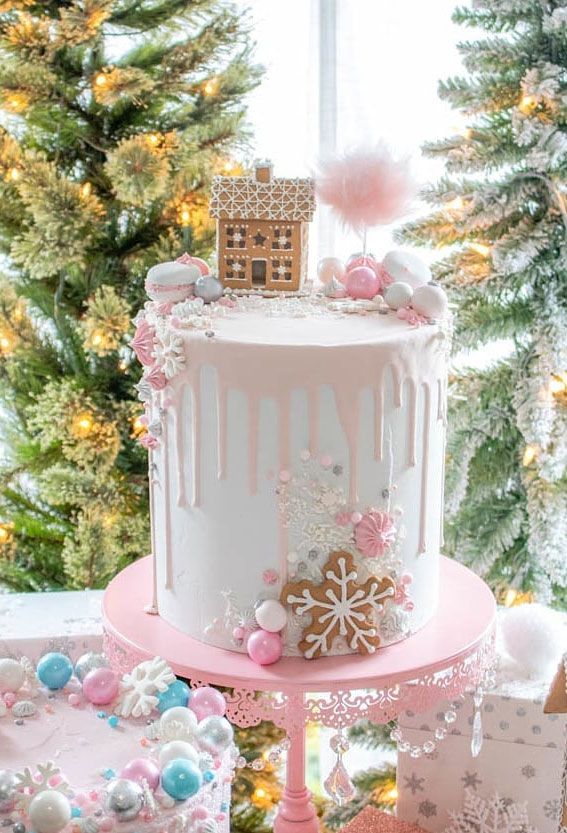 a white and pink cake sitting on top of a table next to a christmas tree