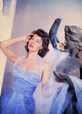 a woman in a blue dress standing next to a statue