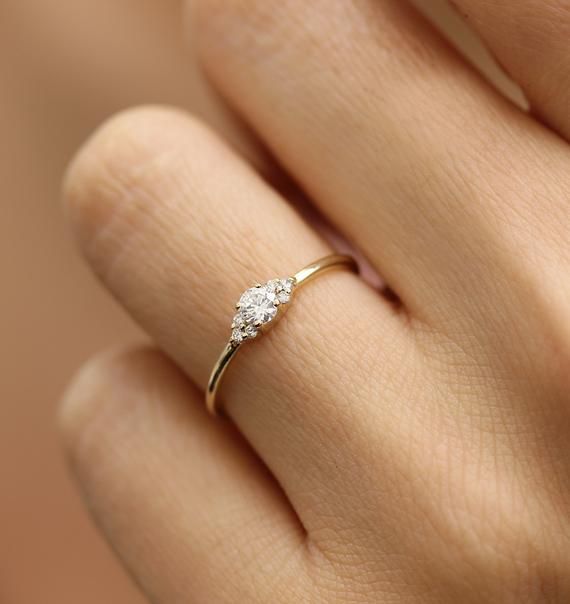 a woman's hand with a diamond ring on top of her finger, showing the side view