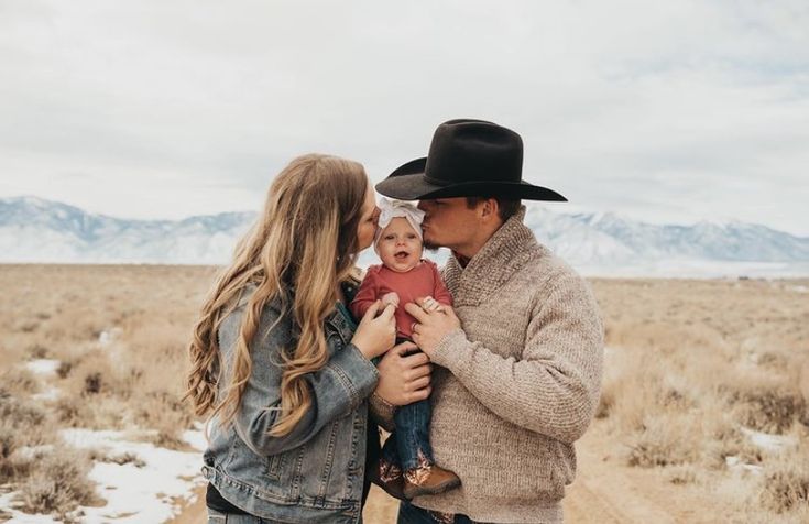 a man and woman holding a baby in the desert