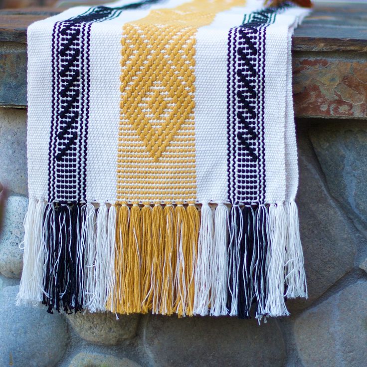 a yellow and black blanket hanging on a stone wall