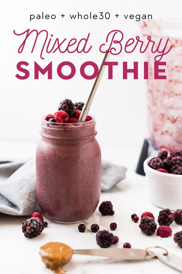 a smoothie in a mason jar with berries on the side and a spoon next to it