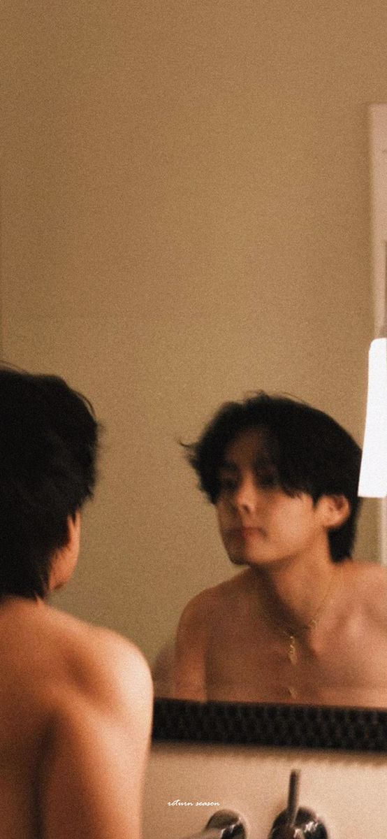 a shirtless man is looking at himself in the mirror