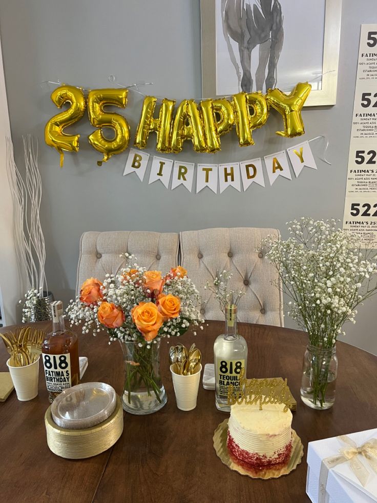 a wooden table topped with a cake and vases filled with flowers next to a sign that says 25 happy birthday