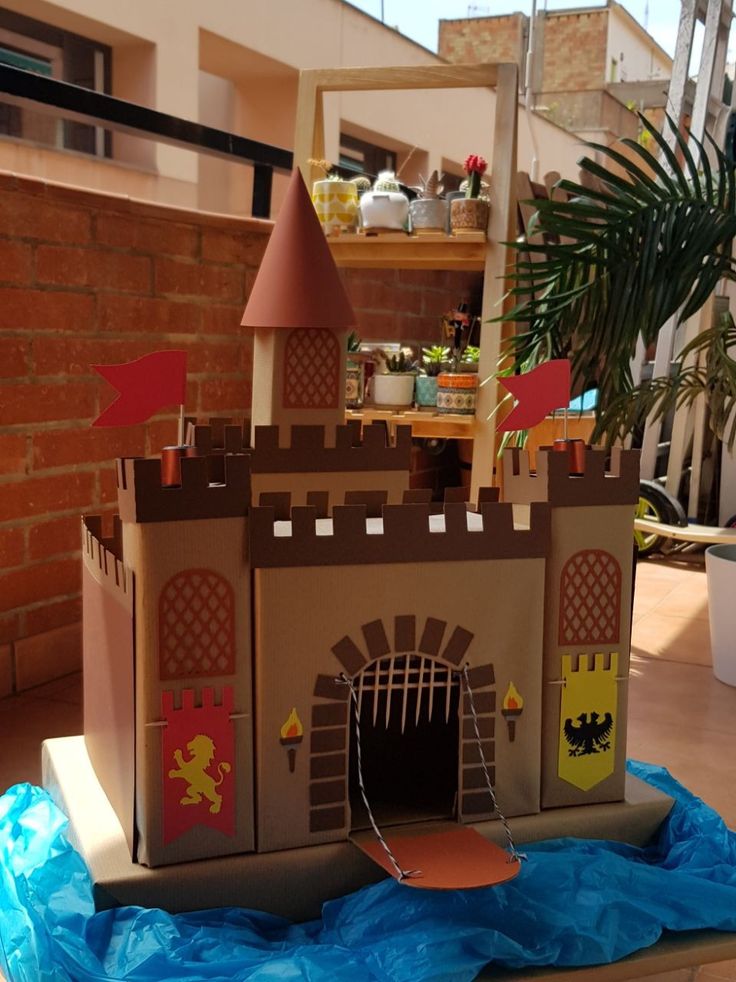 a castle made out of cardboard sitting on top of a blue tarp next to a potted plant