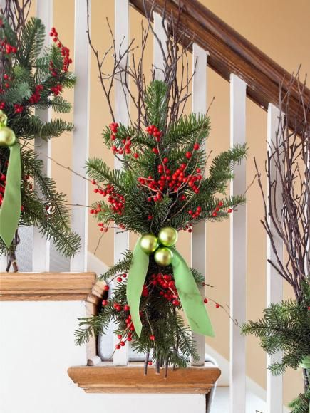 christmas decorations on the banisters and stairs are decorated with greenery, red berries, pine cones and green bow