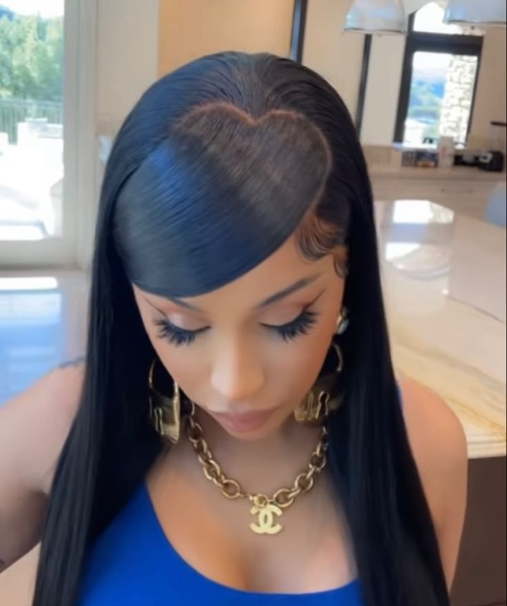 a woman with long black hair wearing gold hoop earrings and a blue top is looking down at her phone