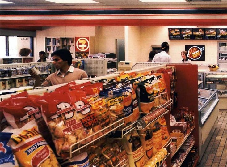 a man is standing in front of the food section of a grocery store with customers