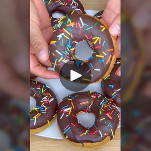 two hands holding donuts with chocolate frosting and sprinkles