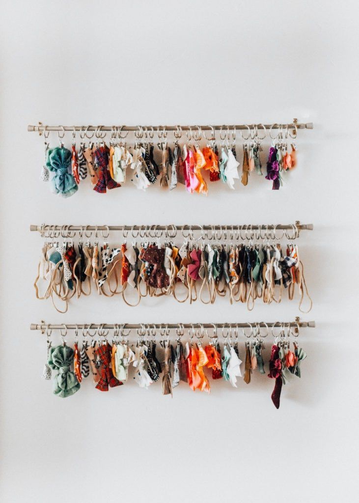 several pairs of scarves hanging from hooks on a wall