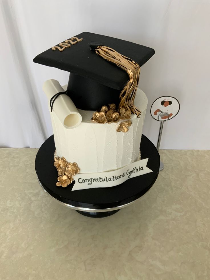 a graduation cake that is decorated with gold and black decorations, including a mortare