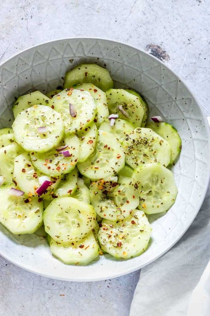 a white bowl filled with sliced cucumbers and spices