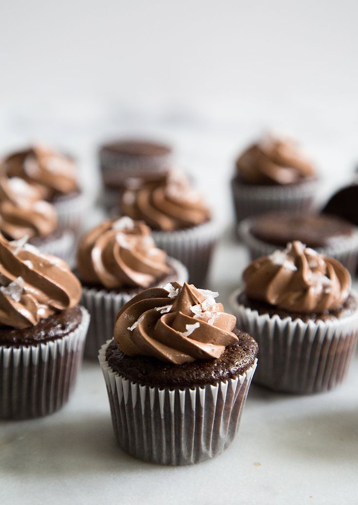 chocolate cupcakes with frosting and sprinkles sitting on a table