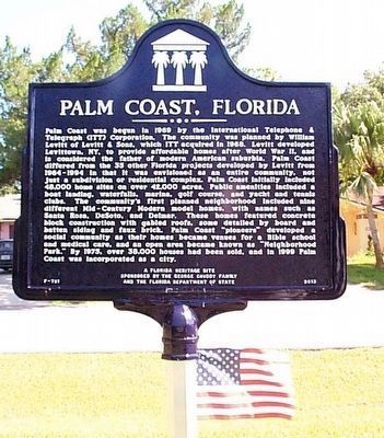 a sign in front of a flag on the side of a road that says palm coast, florida