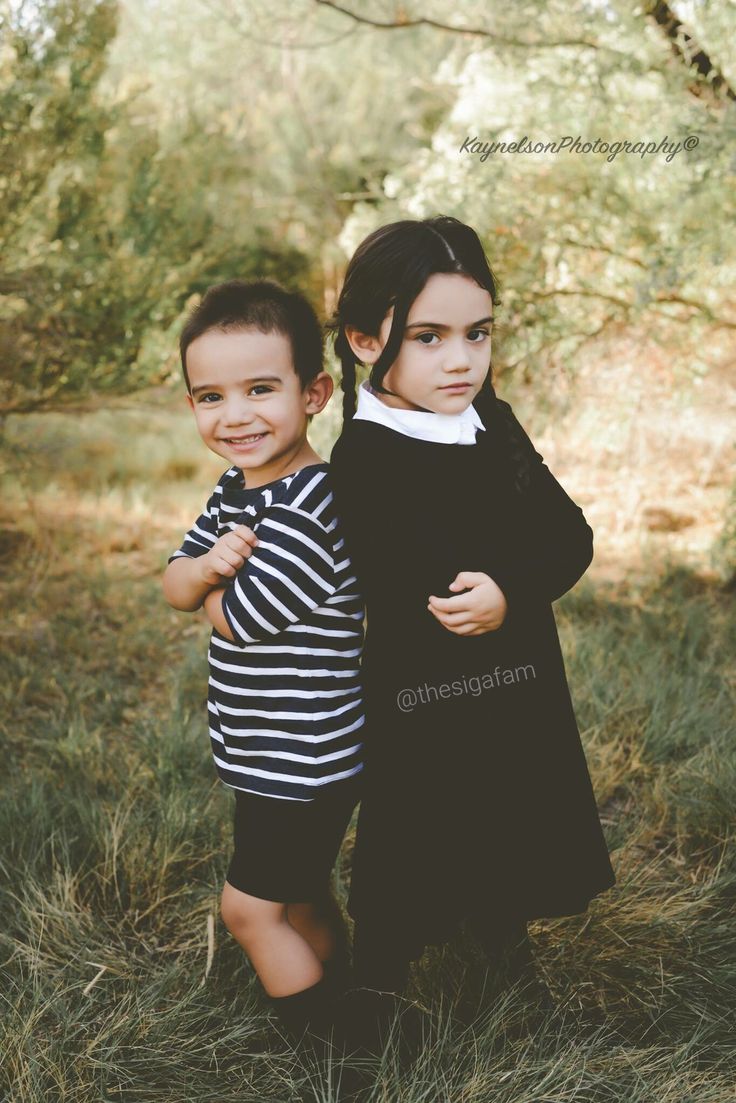 two young children standing next to each other in the grass