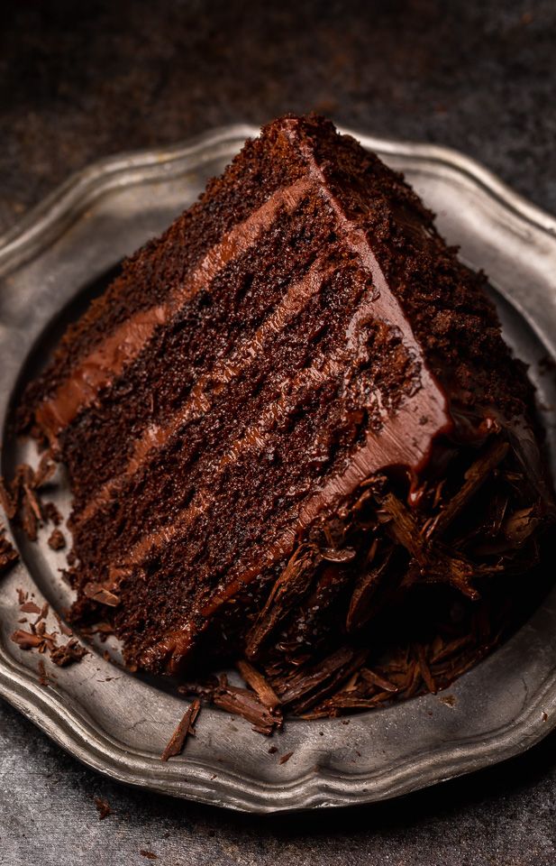 a piece of chocolate cake on a silver platter with the rest of it cut in half