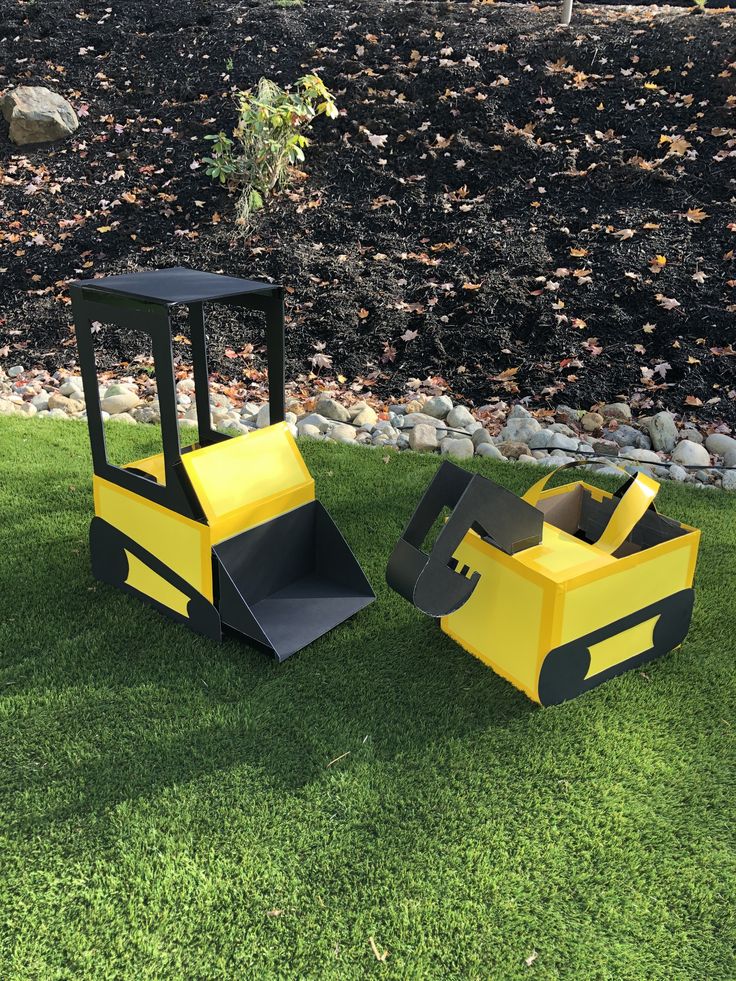 two cardboard construction vehicles sitting in the grass