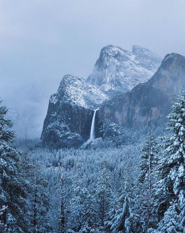 the mountains are covered in snow and there is a waterfall coming out of the mountain