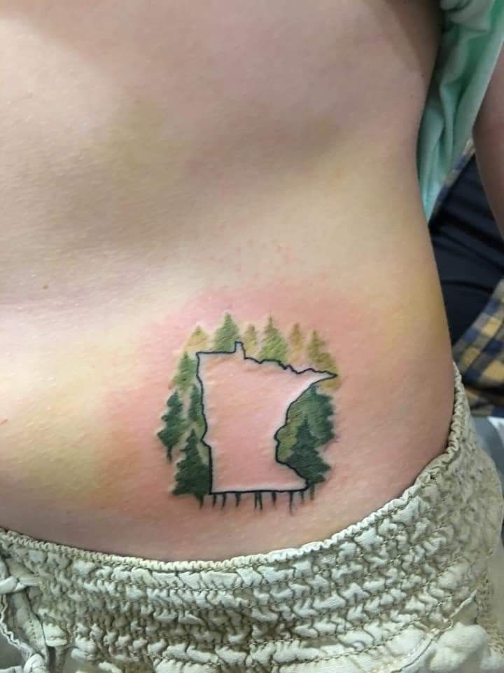 a woman's stomach with trees on it and the outline of a forest behind her