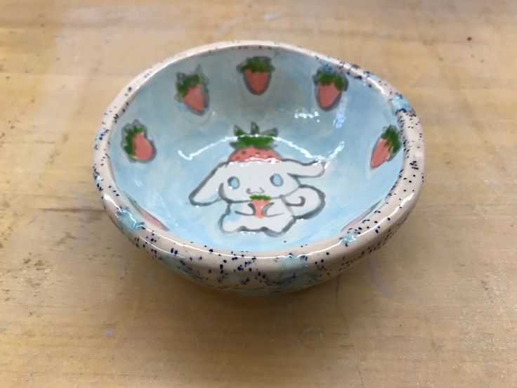 a bowl with strawberries painted on the side and an image of a bunny inside it