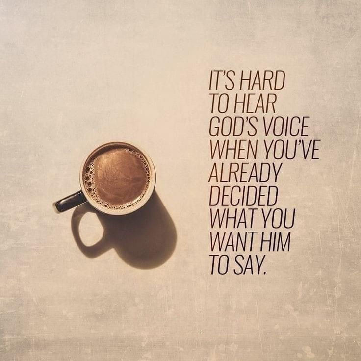 a cup of coffee sitting on top of a table next to a quote that says it's hard to hear god's voice when you've already decided what you want