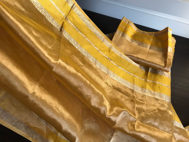 This is a beautiful handloom tissue silk organza saree in tissue gold/ mustard yellow with katan silk banarasi borders on either side. Saree has thin horizontal lines across the body and pallu. Saree in finished with yellow colour and tissue gold colour tassels. Saree comes with an unstitched blouse piece similar to the saree. Saree truly shimmers like gold and it is perfect to wear for an outdoor daytime wedding or an evening wedding. Falls and pico are done! All sales are final. Dry clean only. Rekha Saree, Tassels Saree, Saree Yellow, Daytime Wedding, Organza Silk Saree, Banarasi Silk Saree, Horizontal Lines, Silk Cotton Sarees, Yellow Colour