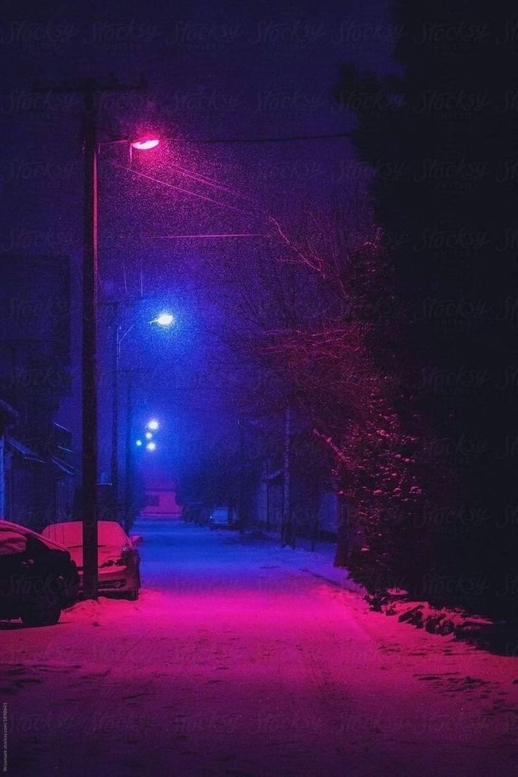 a street light that is lit up in the dark with red lights on it and snow all around