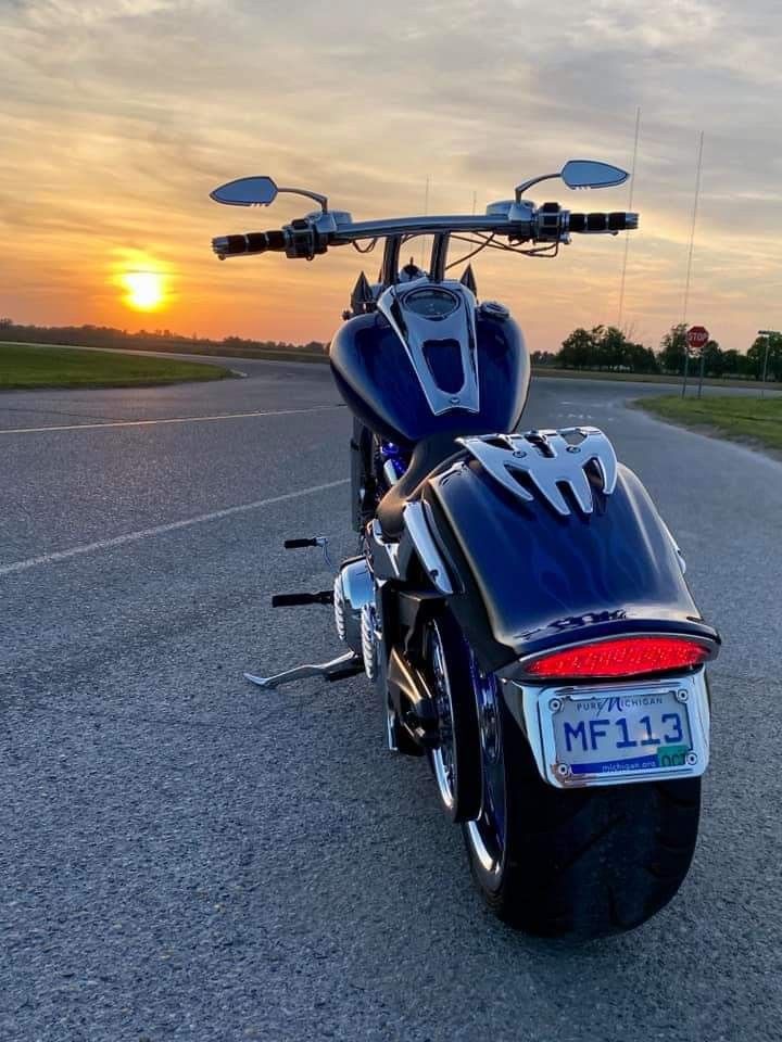 the motorcycle is parked on the road at sunset