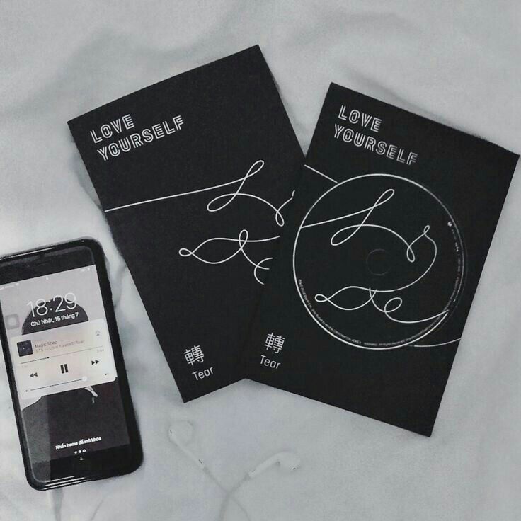 two black notebooks with love yourself written on them next to an iphone and ear buds