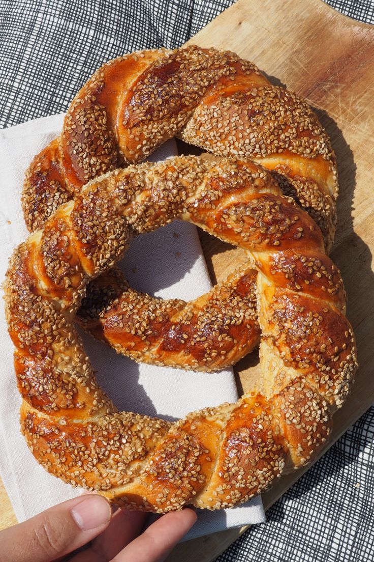 a person is holding a piece of bread with sesame seeds in it on a cutting board