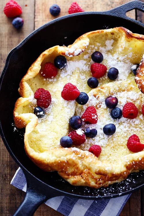 a pancake with berries and powdered sugar in it sitting on a table next to a fork