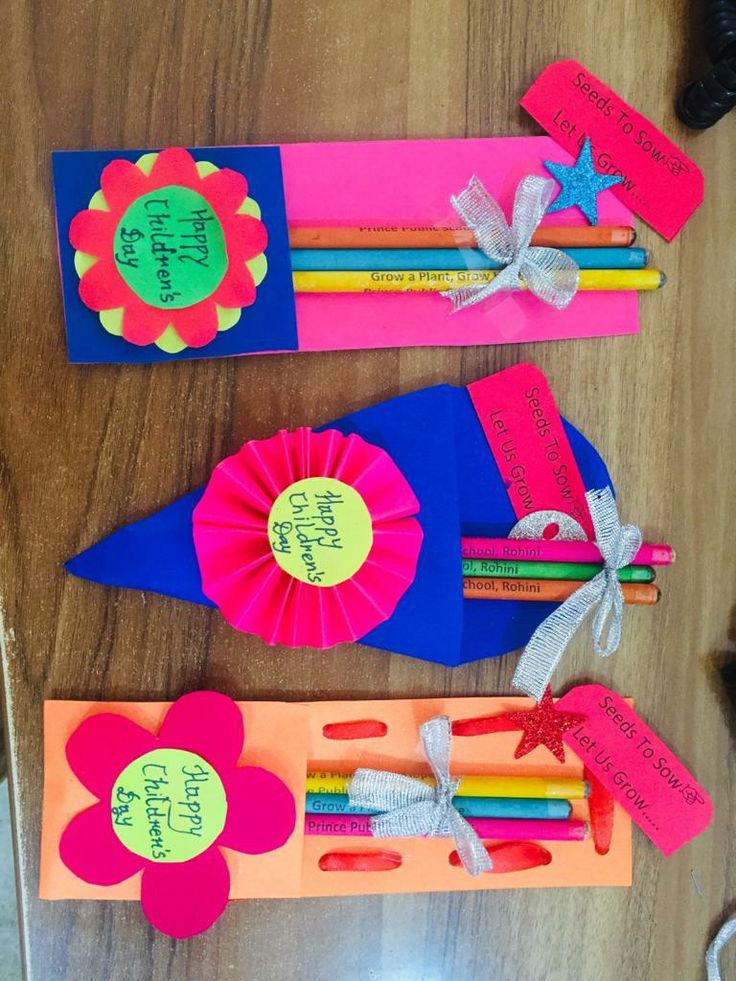 three colorful pencils with flowers and writing on them sitting next to some paper tags