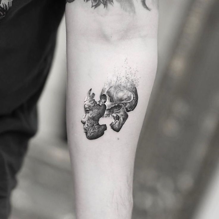 a man's arm with a skull and two skulls tattoo on the left forearm