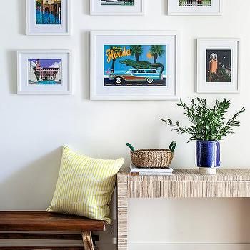 there are many framed pictures on the wall next to a bench with a potted plant