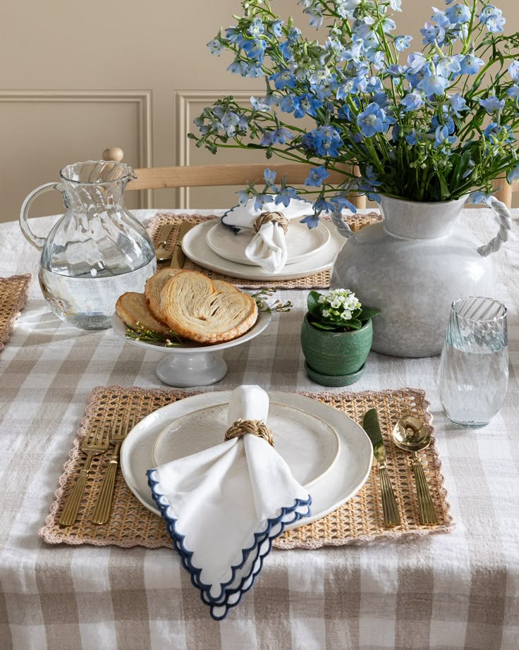 the table is set with blue flowers and dishes