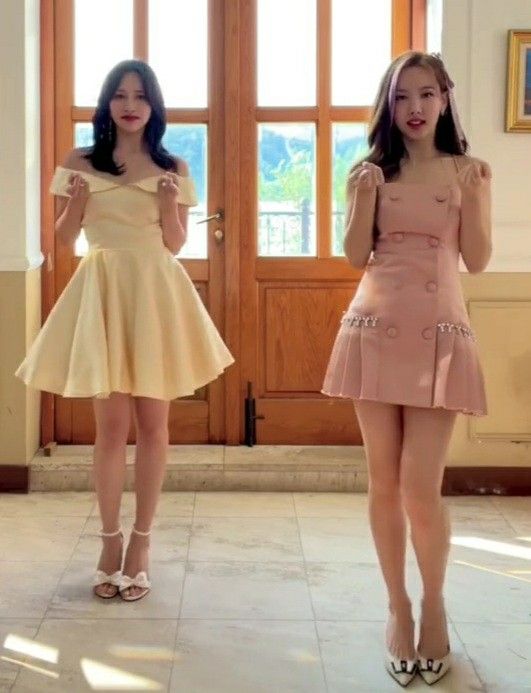 two young women in short dresses standing next to each other with their hands on their hips