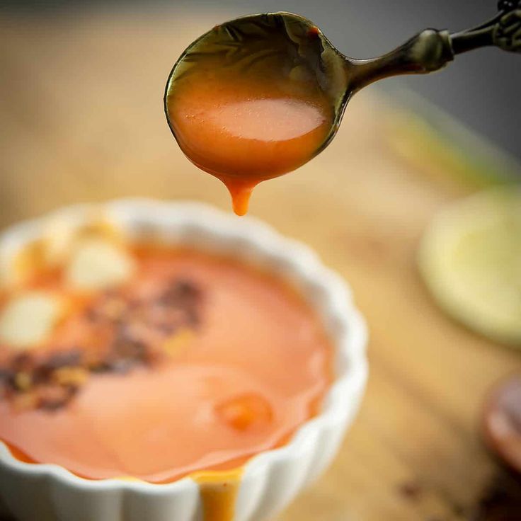 a spoon full of caramel sauce on top of a bowl