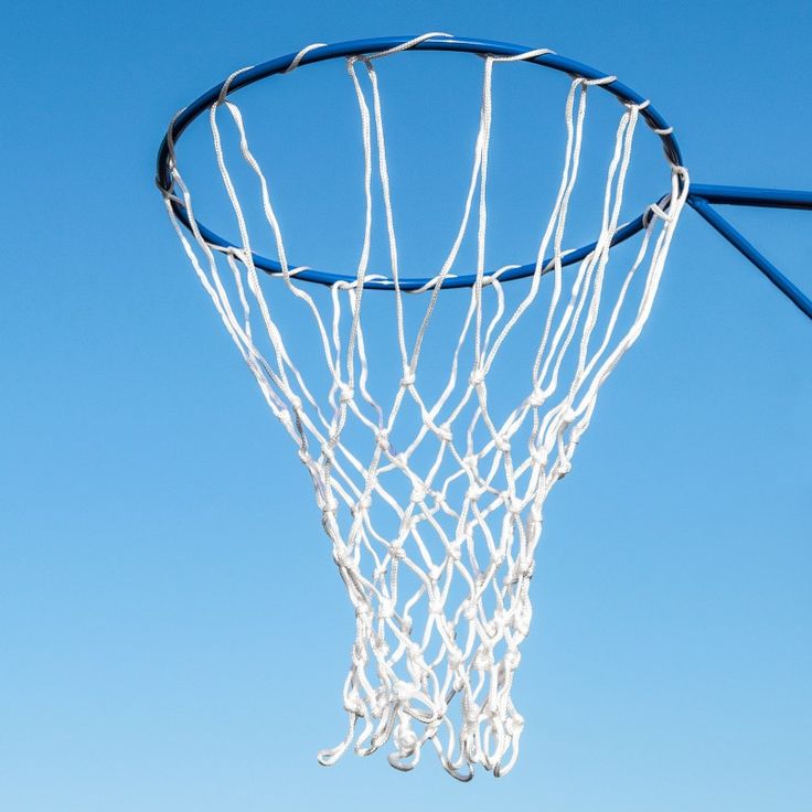 a basketball going through the hoop with blue sky in the backgrouds behind it