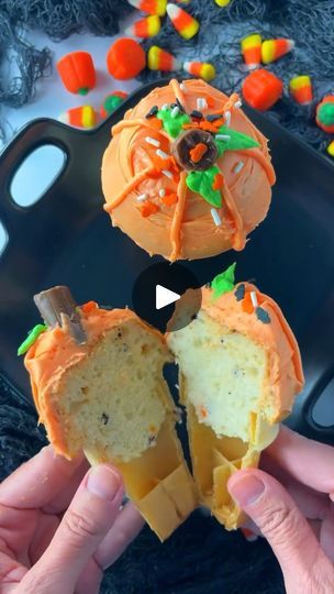 someone is holding an orange cupcake with candy on it and the inside has been cut in half