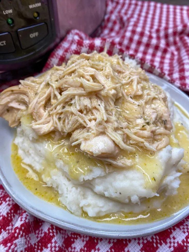 a white plate topped with mashed potatoes covered in gravy next to an instant pressure cooker