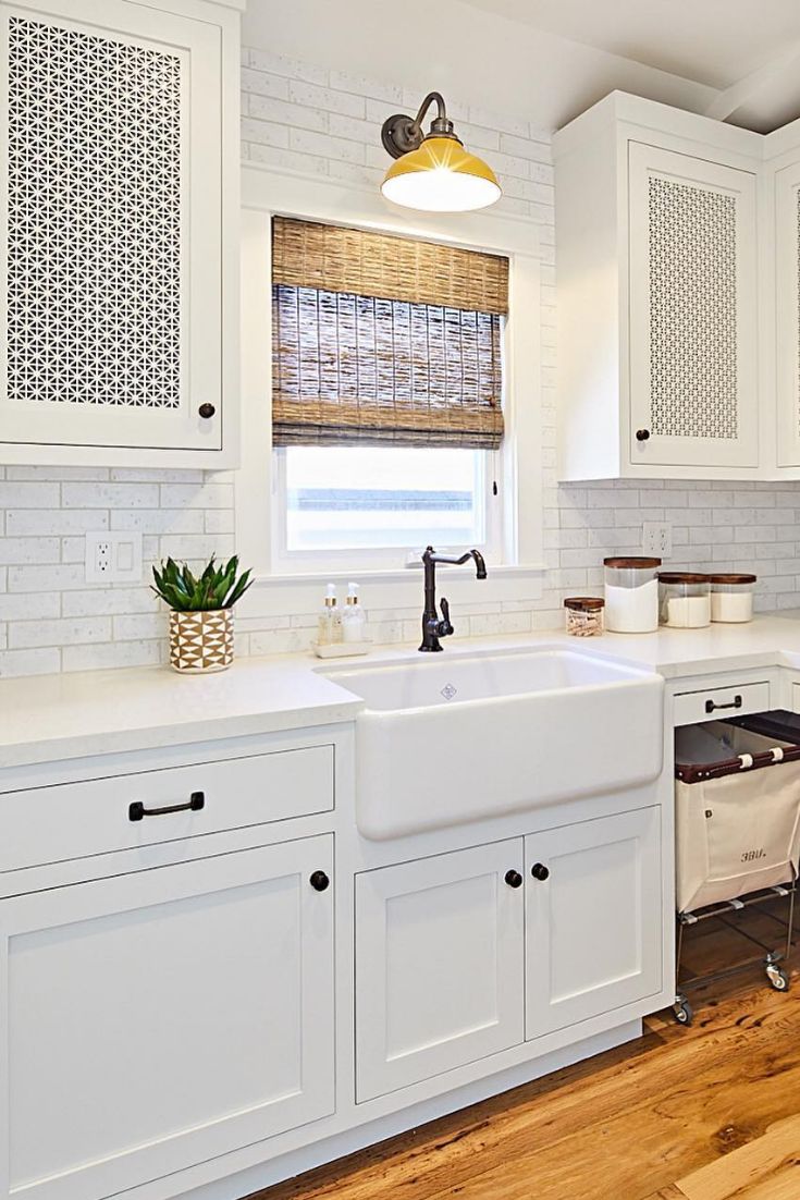 a kitchen with white cabinets and wood flooring is pictured in this image, the sink has an apron style design on it