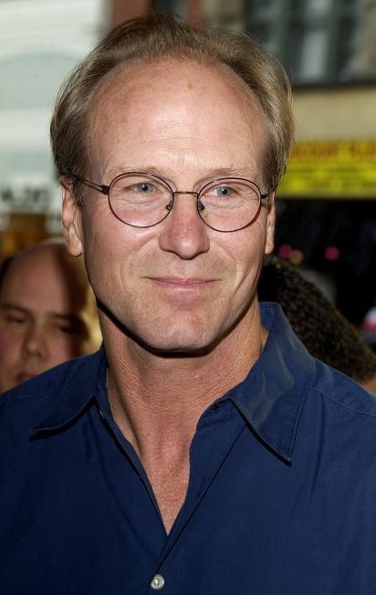 a man with glasses is smiling for the camera while standing in front of a crowd