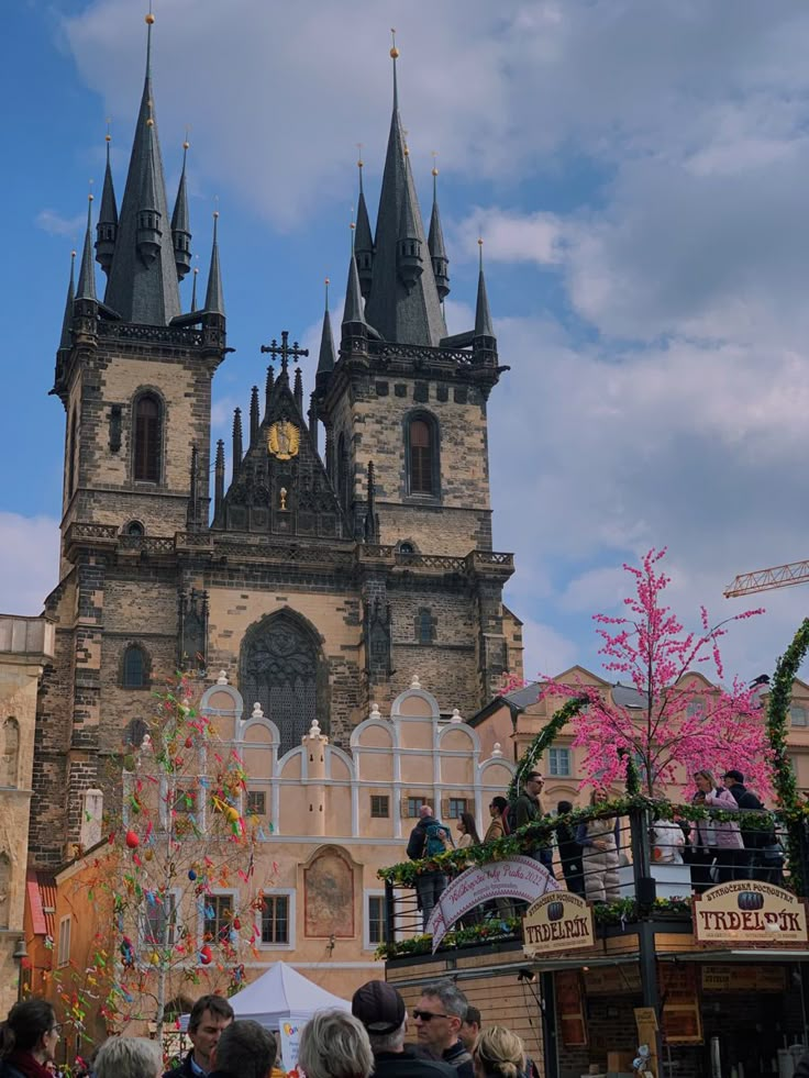 people are standing in front of an old building with towers and spires on it