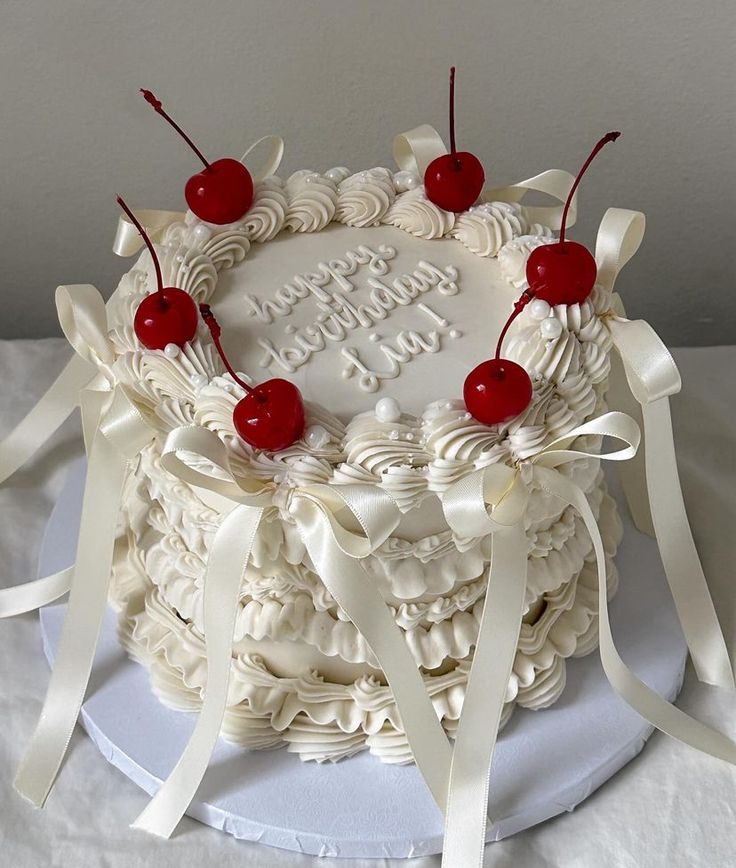 a birthday cake decorated with cherries and ribbons