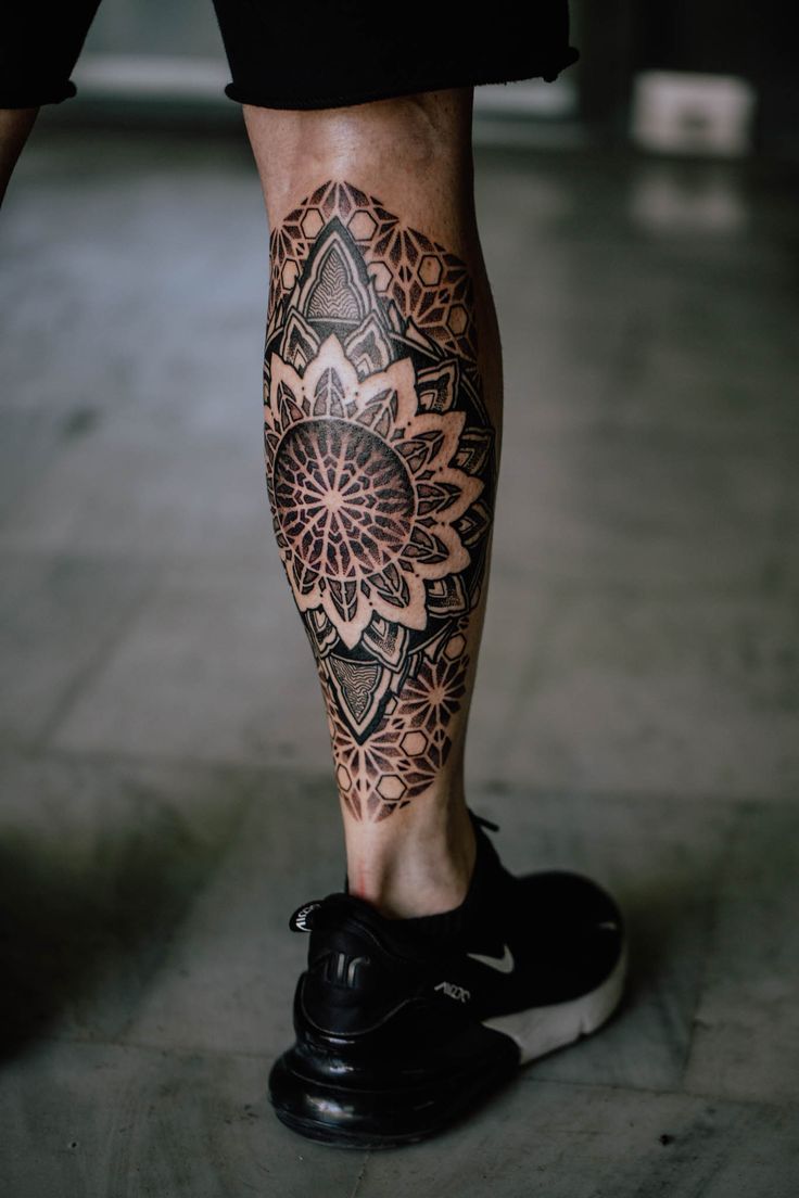 a man's leg with a tattoo on it and a flower in the center